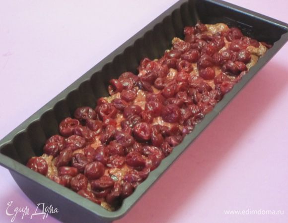 Половину теста выложить в форму для кекса. Выложить вишню, предварительно обваленную в крахмале. Это делается для того, чтобы во время выпекания выделяющийся из вишни сок не очень сильно пропитывал тесто. 