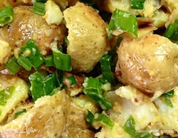 Готовый картофель переместим в большую миску, добавим к нему измельченный зеленый лук, польем соусом и перемешаем.
Теперь при помощи деревянной лопаточки  немного "разобьем" картофель, не в пюре, конечно, а лишь слегка, чтобы кожура лопнула и клубни лучше пропитались заправкой.
И оставляем миску при комнатной температуре минут на 45-60.