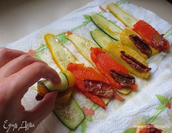 На цукини выкладываем дольку перца, вяленый томат и заворачиваем рулетиком.