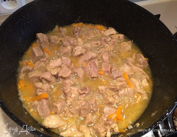 К мясу и овощам добавить специи для плова, посолить по вкусу. Влить в казан воду так, чтобы она покрыла мясо. Тушить на среднем огне 25-30 мин.
