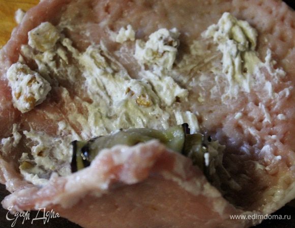 Далее берем мясо, слегка смазываем его начинкой, на край кладем рулетик баклажана и все вместе сворачиваем рулетом.