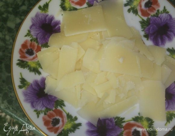 Картофелечисткой строгаем сыр хаотичными кусочками.