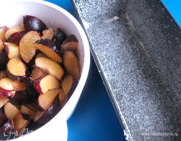 Поместить сливы в смазанную сливочным маслом и посыпанную 2 ст. ложками (35 г) сахара форму для выпекания. Обратить внимание на этот момент, форма должна «держать напыление» из песка равномерно (стенки и дно формы).