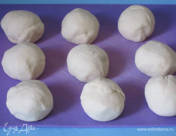 Разделить тесто на 9 частей. Скатать их в шарики. Уложить на посыпанную мукой доску. Накрыть полотенцем и оставить на 40 минут.