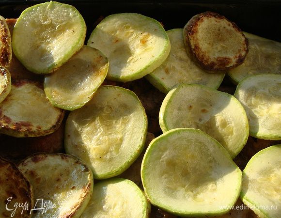 Небольшой кабачок нарезать тонкими ломтиками и обжарить на сковороде с двух сторон. Выложить сверху свинины.
