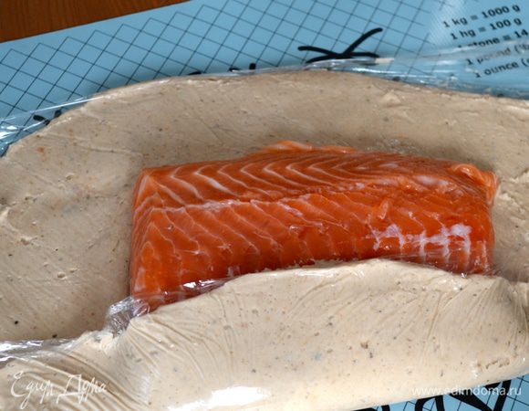 Снять верхнюю пленку и положить филе семги (можно по желанию слегка посолить). Помогая себе нижним слоем пленки, завернуть филе как в конвертик в полученную хлебно-рыбно-грибную массу... ))) Присыпать сверху кунжутными семечками. 