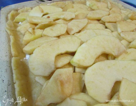 Тесто разделить на 2 неравные части. Выложить большую часть теста в прямоугольную форму, оформляя небольшие бортики. Тесто присыпать крахмалом и разложить яблоки. 