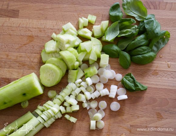 Такой салат рекомендуется начинать нарезать с более твердых, плотных овощей. Поэтому первым делом моем и начинаем нарезать зеленый лук и огурец. Затем добавить и порубить листья базилика. 