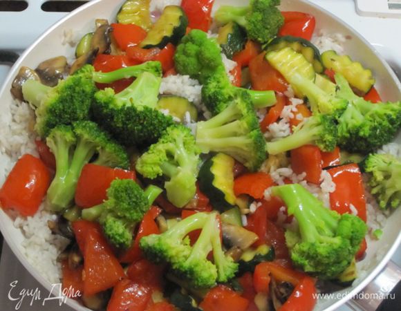 Переложить обжаренные овощи в сковороду с рисом, добавить брокколи.