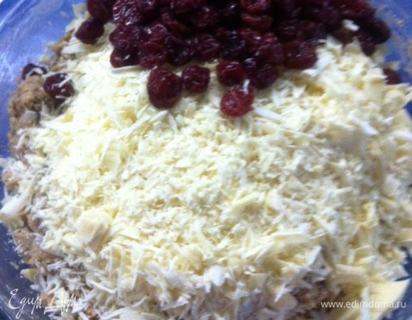 Затем всыпать белую шоколадную стружку и клюкву. Перемешать лопаткой.