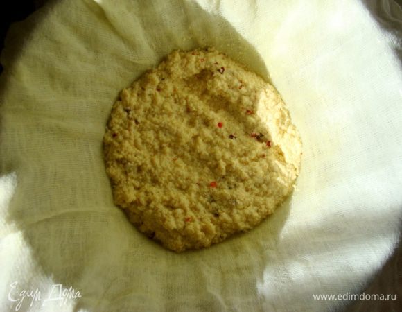 Дуршлаг зафиксировать в кастрюле, сверху распределить марлю в два слоя и постепенно выложить сырную массу.