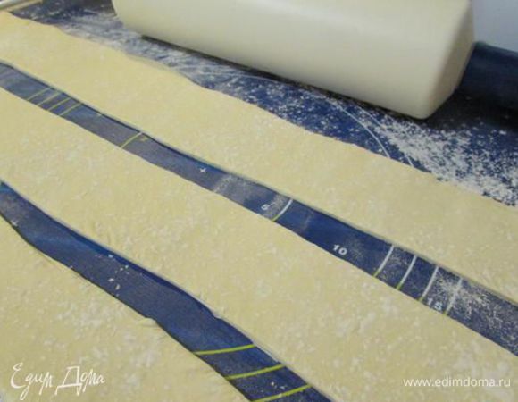 Тесто разморозить. Пласт теста слегка раскатать. Разрезать пласт теста на полоски шириной 4-5 см.