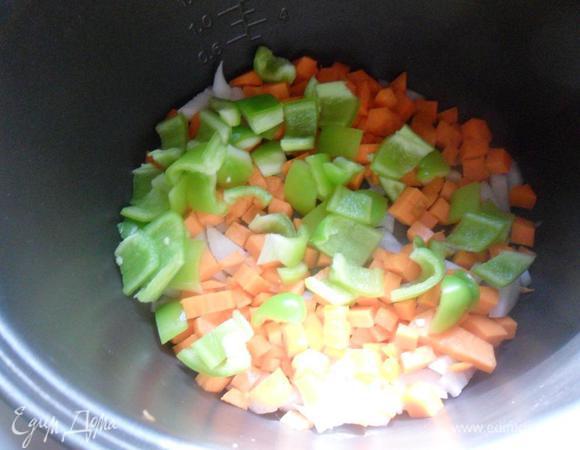 Очистить репчатый лук. Вымыть и очистить морковь и болгарский перец. У перца удалить семенную коробочку.  Нарезать овощи кубиками.
В чашу мультиварки налить растительное масло, выложить овощи, включить режим "Выпечка/Жарка" и готовить 3 - 5 минут при открытой крышке помешивая.