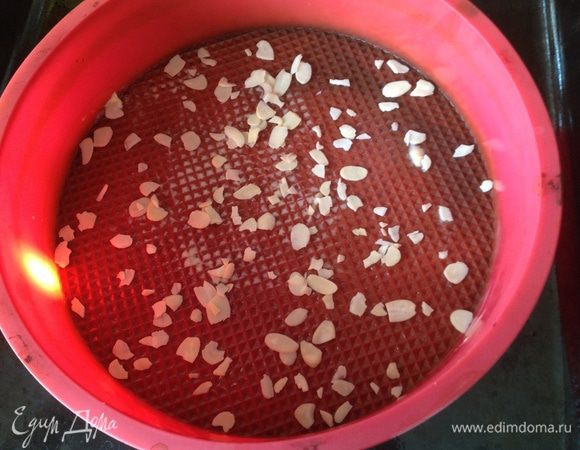 Круглую форму смазать маслом и посыпать миндальными пластинками