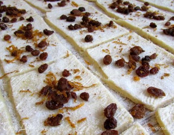 Через час, тесто еще раз вымесить. Рабочую поверхность присыпать мукой,   раскатать тесто в пласт размером примерно 50х50см. Тесто смазать мягким сливочным маслом. Разрезать тесто на прямоугольники примерно 8х10см. Посыпать сахаром (5 ст. л.), сверху распределить смесь из изюма и апельсиновой цедры. 