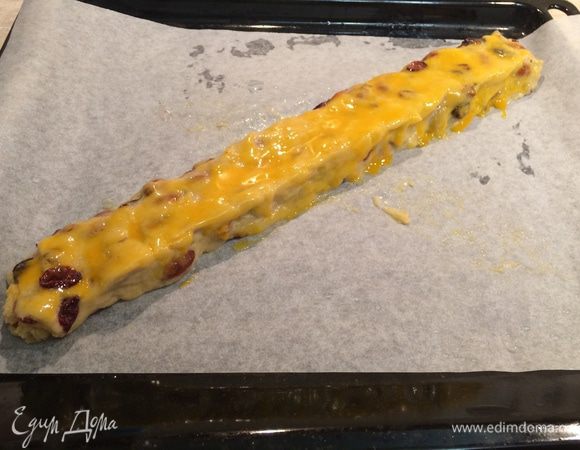 Противень застелить бумагой для выпечки. 
Влажными руками сформировать из теста батон, выложить на противень.
Желток взбить вилкой и с помощью кисточки смазать тесто со всех сторон.