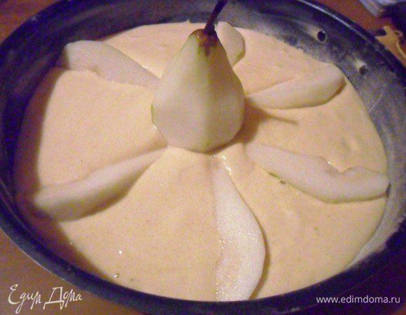 Форму диаметром 24 см смазать маслом и присыпать мукой. В форму влить в тесто. В центр установить целую грушу, дольки азложить вокруг.