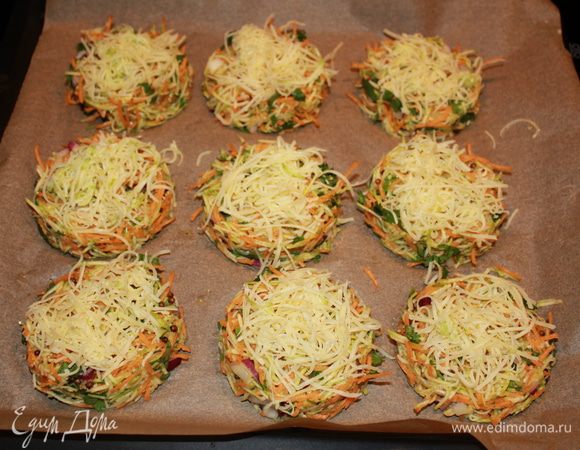 Разогреть духовку на 180 градусов. С помощью кондитерского кольца сформировать оладушки на пергаменте. Сверху выложить натёрный сыр. 