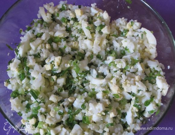 Для начинки отварить 5 яиц вкрутую, очистить, остудить, мелко нарезать. Добавить мелко нарезанный зеленый лук, отварной рис, растопленное сливочное масло. Посолить, поперчить.