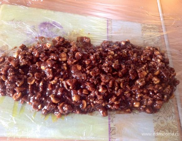 Рабочую поверхность выстелить в 2-3 слоя пищевой пленкой и выложить получившуюся смесь. Сформировать руками форму колбасы и завязать ленточками по краям.