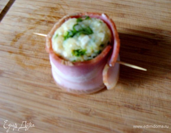 Столовой ложкой взять картофельную массу, сформировать шарик, потом преобразовать его в нечто, напоминающее цилиндр, обмотать беконом, зафиксировать шпажкой. Массу бекона не написала, зависит от его типа и размера.