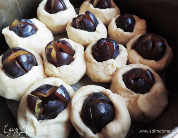 Тесто обминаем, делим на 12 частей. Из каждой части делаем лепешечку и оборачиваем вокруг сливы до половины. Края лепешки произвольно слепливаем. Полученные "пирожки" выкладываем в круглую форму диаметром 24-26см, дно которой выстилаем бумагой для выпечки. а бортики смазываем растительным маслом. Оставляем пирог на расстойку еще на 30-40 минут.