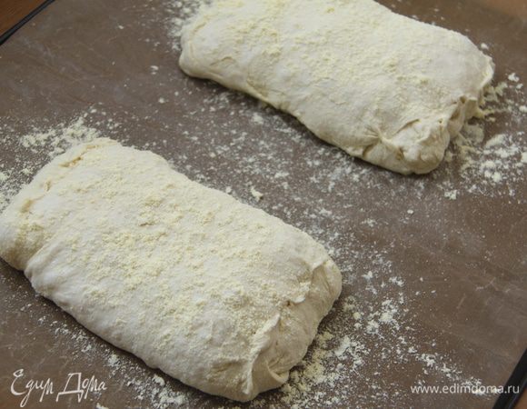 Выложить заготовки хлеба на присыпанный мукой антипригарный лист. Края каждой чиабатты защипать. Сверху слегка присыпать кукурузной мукой. Оставить на расстойку на 45-60 минут под полотенцем.
