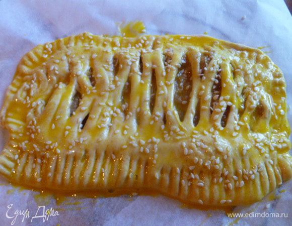 Переносим на противень с пергаментом, обильно смазываем взбитым желтком с 1 ст.л. молока. В дырочки выливаем остаток и сверху посыпаем кунжутом.