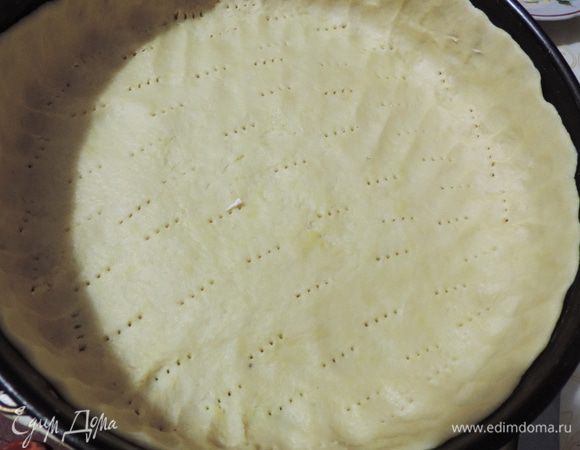 Делим тесто на 1/3 и 2/3 части. Большую часть руками распределяем по форме диаметром 26 см, смазанной растительным маслом. Тесто накалываем вилкой. Бортики делаем на всю высоту формы. Выкладываем начинку. Выступающие края теста загибаем на начинку.