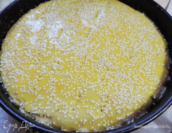 Оставшуюся часть теста раскатываем на бумаге или силиконовом коврике, переносим на пирог и аккуратно отделяем бумагу (коврик) от теста. Желток взбиваем вилкой с маслом, смазываем верх пирога и посыпаем кунжутом.