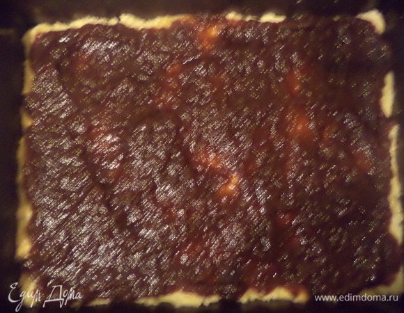 Прямоугольную форму для выпечки смазать маслом, присыпать мукой. Тестом выстелить форму, в нескольких местах проткнуть вилкой. Намазать корж повидлом. Выпекать до полуготовности при температуре 180 градусов 15 - 20 минут.