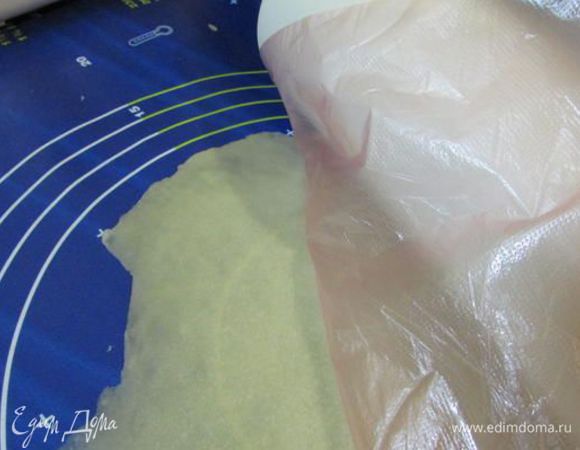 Каждый комочек теста раскатать в тонкий, очень тонкий пласт (у меня через него проглядывает круг на разделочном коврике). Удобно это сделать через целлофановый мешочек. 