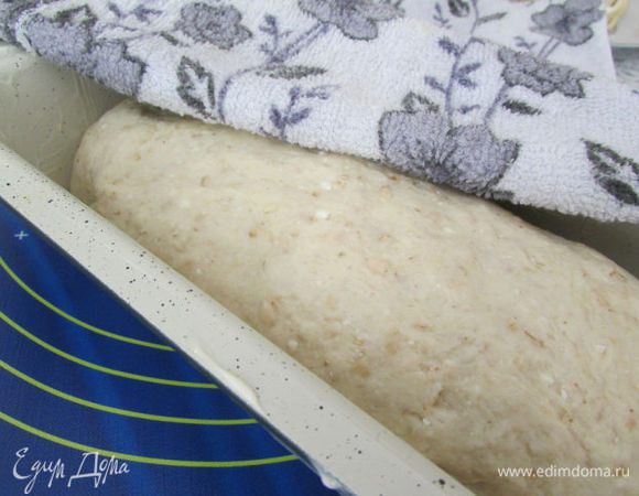 Смажьте сливочным маслом форму. Выньте тесто из миски и слегка обомните. Сформируйте буханку, подгибая края внутрь, и положите хлеб в форму. Накройте полотенцем и оставьте на расстойку на 15-20 минут. Тесто должно подняться.