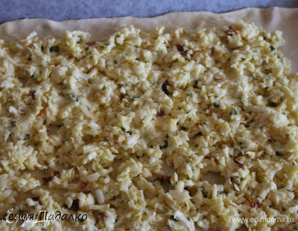 Тесто разморозить. Противень застелить пергаментом, смазать растительным маслом. Половину теста раскатать, по размеру противня. Сверху выложить начинку. Разровнять руками.