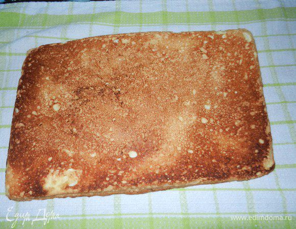 Присыпать полотенце сахарной пудрой, быстро извлечь выпеченный корж на полотенце, аккуратно отделяя от пергаментной бумаги (Мой личный совет - покупайте пергам. бумагу хорошего качества, чтобы она не рвалась в процессе работы, на ней лучше никогда не экономить).