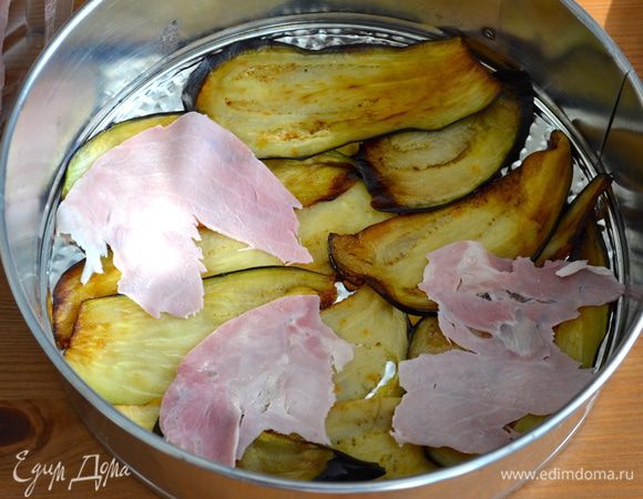 Обычно я запекаю Пармиджану в керамической форме для выпечки. Но в данном рецепте рекомендовалось запечь баклажаны в разъемной форме (по-моему только для того, что после готовое блюдо можно красиво и празднично поставить на стол! )))) Итак, выложить на дно формы немного соуса, сверху выложить слой из баклажанов и ветчину...