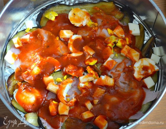 Затем выложить сверху нарезанный кусочками сыр и кружочки яиц. Обильно смазать томатным соусом. Повторять таким образом слои запеканки до окончания ингредиентов. Несколько долек яйца оставить для финального украшения...
