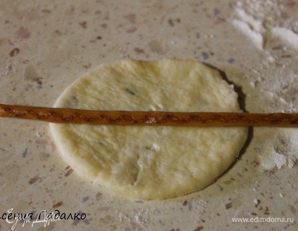 Отщипываем 1/2 часть теста, на подпыленном мукой столе раскатываем пласт. Стаканом вырезаем кружок. На середину кладем соленую соломку.