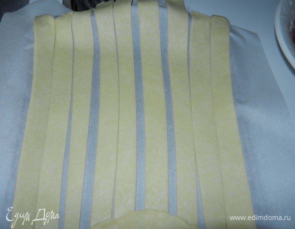 Вторую половинку теста раскатать диаметром чуть больше диаметра вашей формы для выпечки. Порезать на длинные полоски шириной около 2 см. (я не считала, но получилось около 14 полосок). Выложить их на лист с пергаментом и отправить в холодильник на 30 минут.
Включить духовку разогреться на 200 гр. С.
