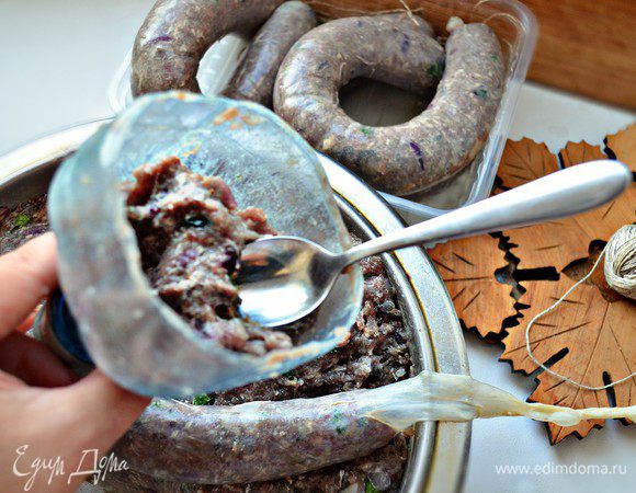 Возьмите пластиковую бутылку, срежьте верхнюю 1/3 часть, её мы и будем использовать для формирования купат. Такое незамысловатое приспособление мне даже больше нравится, нежели специальная насадка на мясорубку, которая у меня тоже имеется. Итак, на горлышко бутылки наденьте чреву. В бутылку положите фарш и с помощью ложки проталкивайте в горлышко, наполняя тем самым чреву. Старайтесь равномерно распределять фарш внутри чревы и слишком плотно не набивать её (во время готовки чрева может лопнуть).
С помощью кулинарной нити завяжите концы.