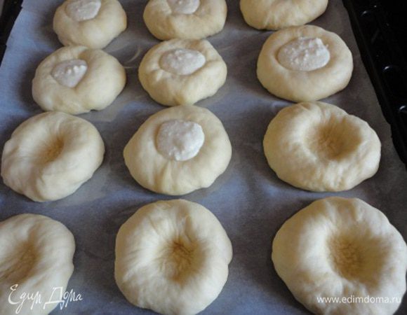 Деревянным пестиком диаметром 5 см сделайте углубление в каждой заготовке. В углубление выдавите творожную начинку из кондитерского мешка (я выкладывала просто ложечкой). Оставьте ватрушки на 20-25 минут еще подойти, смажьте желтком, смешанным с молоком. Выпекайте при температуре 190-200 градусов 20 минут.