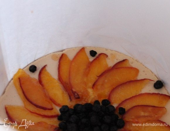 Займемся украшением, персик нарезать тонкими ломтиками, выложить веером по краю торта, в середину положить чернику.Желатин залить водой и оставить до набухания, потом подогреть до его полного растворения. Но не кипятить. Добавить сахар и лимонную кислоту. Перемешать и остудить. Аккуратно заливаем верх торта и убираем в холодильник на 1 час.