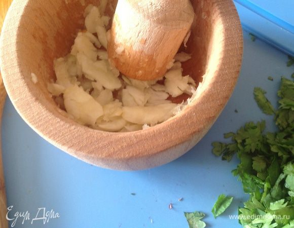 ПИКАДА:
 В ступке надо раздавить чеснок. (Чеснок я очень люблю и кладу не 3-4 зубчика, а почти всю головку) 
У петрушки стебли удаляем и листья измельчаем. Иногда я добавляю и небольшой пучок кинзы. Хотя тут на любителя.