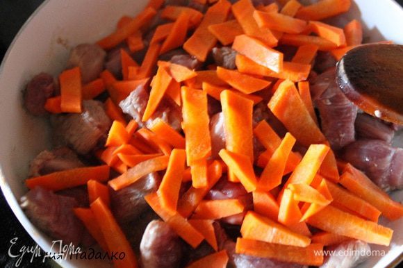 Филе грудки нарезать средними кубиками, выложить в разогретую сковороду. Добавить нарезанную морковь. Перемешать и обжаривать до легкого золотистого цвета.