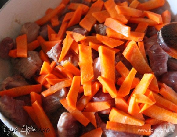 Филе грудки нарезать средними кубиками, выложить в разогретую сковороду. Добавить нарезанную морковь. Перемешать и обжаривать до легкого золотистого цвета.