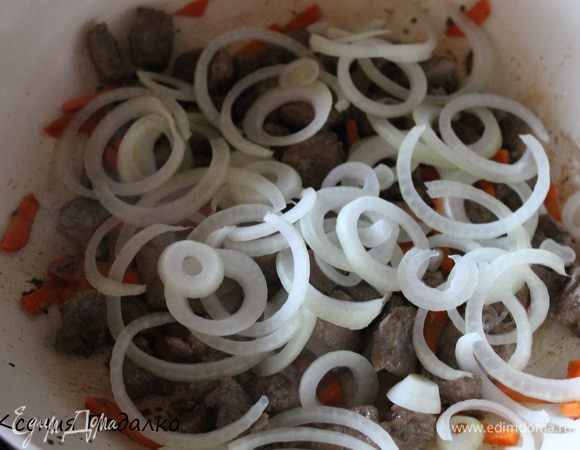 Луковицу нарезать кольцами и добавить в сковороду. Обжаривать все вместе 5 минут.