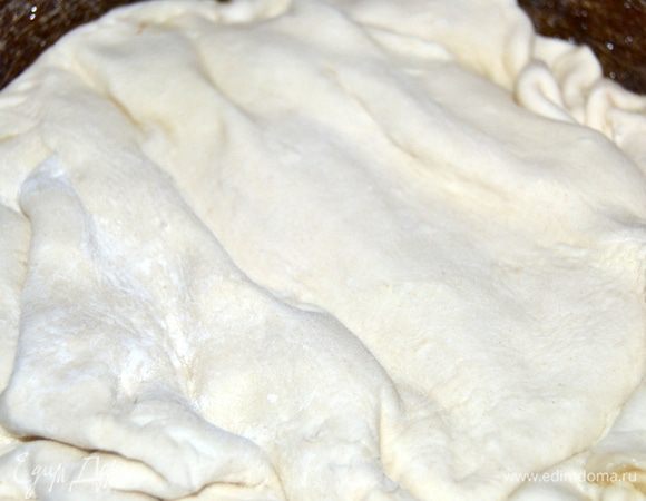 Тесто раскатать по размеру. Достать из духовки сковороду и накрыть баклажаны тестом, аккуратно подгибая края вниз.