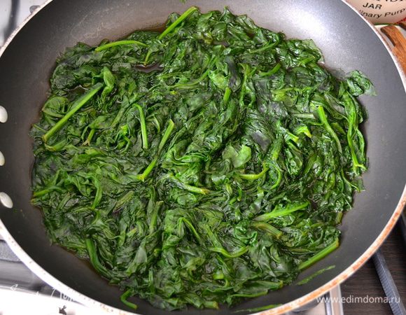 Шпинат вымыть в холодной воде. Большую глубокую сковороду поставить на огонь. Шпинат выложить в сковороду (дополнительно воды не добавлять) и готовить около 5-7 минут, пока не уменьшится в объеме и не потемнеет. Готовый шпинат слегка отжать от лишней жидкости и выложить на тарелку.  