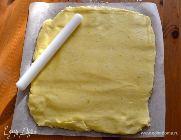 На рабочий стол положить лист пекарской бумаги. Смазать бумагу растопленным сливочным маслом и присыпать слегка мукой. Выложить картофельное "тесто" и раскатать его в пласт равномерной толщины размером 30 Х 25 см.