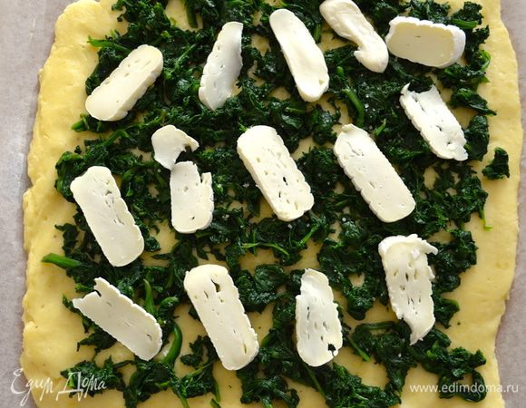 Нарезать пластинками сыр и тоже распределить поверх шпината. Присыпать все тертым Пармезаном.